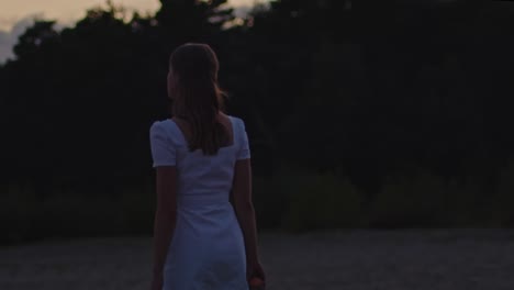 Attractive-woman-walking-away-and-turning-around-in-beautiful-sand-dunes-at-dusk