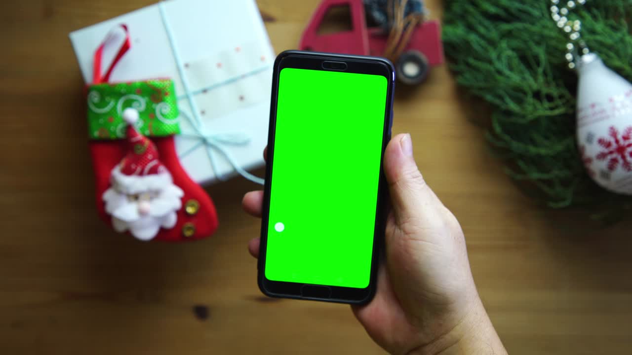 hombre con pantalla verde teléfono inteligente contra regalo de navidad en fondo de madera