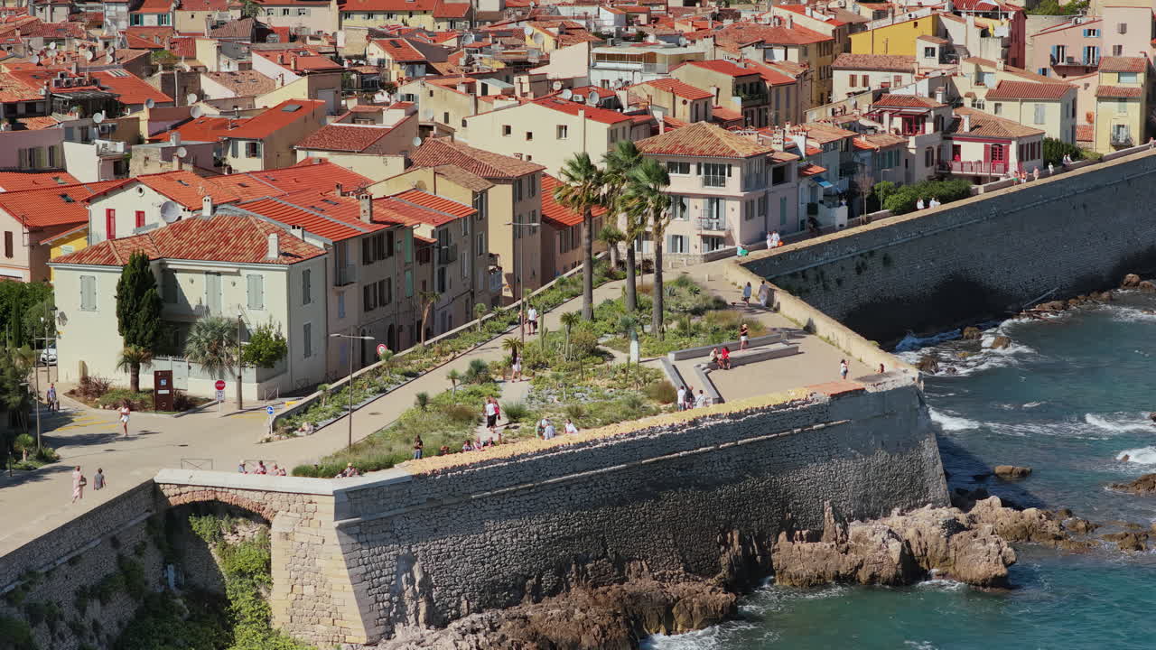 Vista aerea da drone della città vecchia di Antibes con tetti in terracotta, palme e fortificazioni medievali che si affacciano sul Mar Mediterraneo