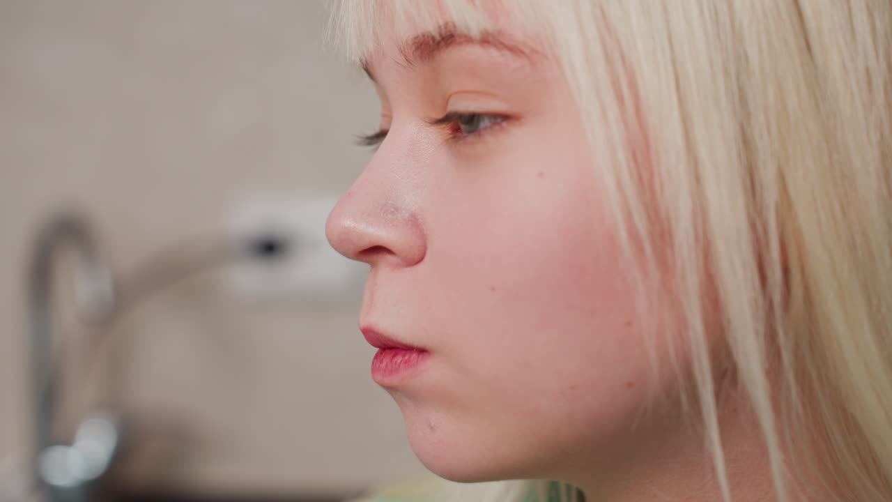 close up of fair skin girl eating chips indoors, natural expression, casual moment, light soft focus background, detail on lips and cheek, relaxed atmosphere, domestic scene, snack time enjoyment