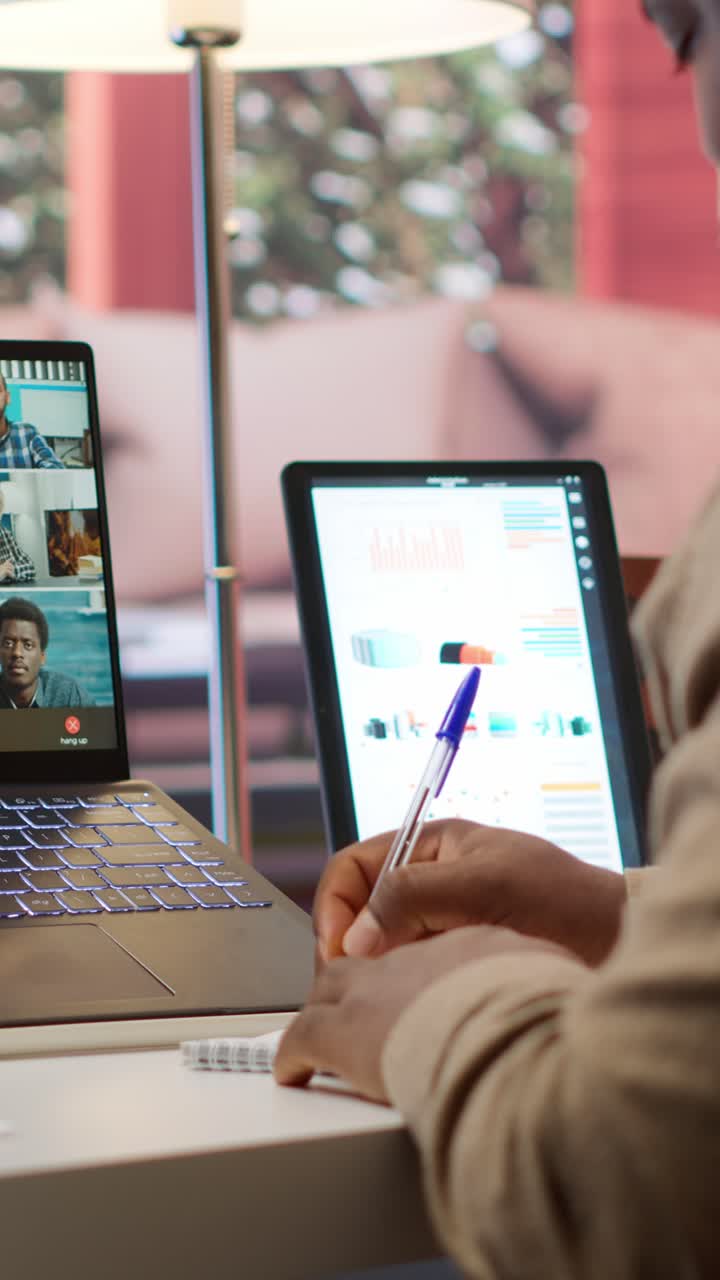 Persona tomando notas durante una videollamada en línea con laptop y tablet.