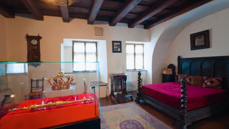 cozy room with big wooden bed, fireplace and golden crown display. bedroom interior in bran castle, romania.