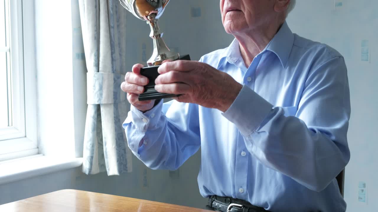 고위 백인 남자가 트로피를 점검하고 있습니다.