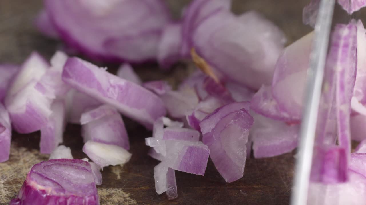 Primo piano di scalogni rossi tagliati con il coltello su tagliere