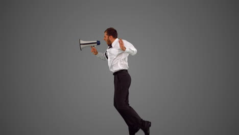 businessman holding megaphone and jumping on grey background