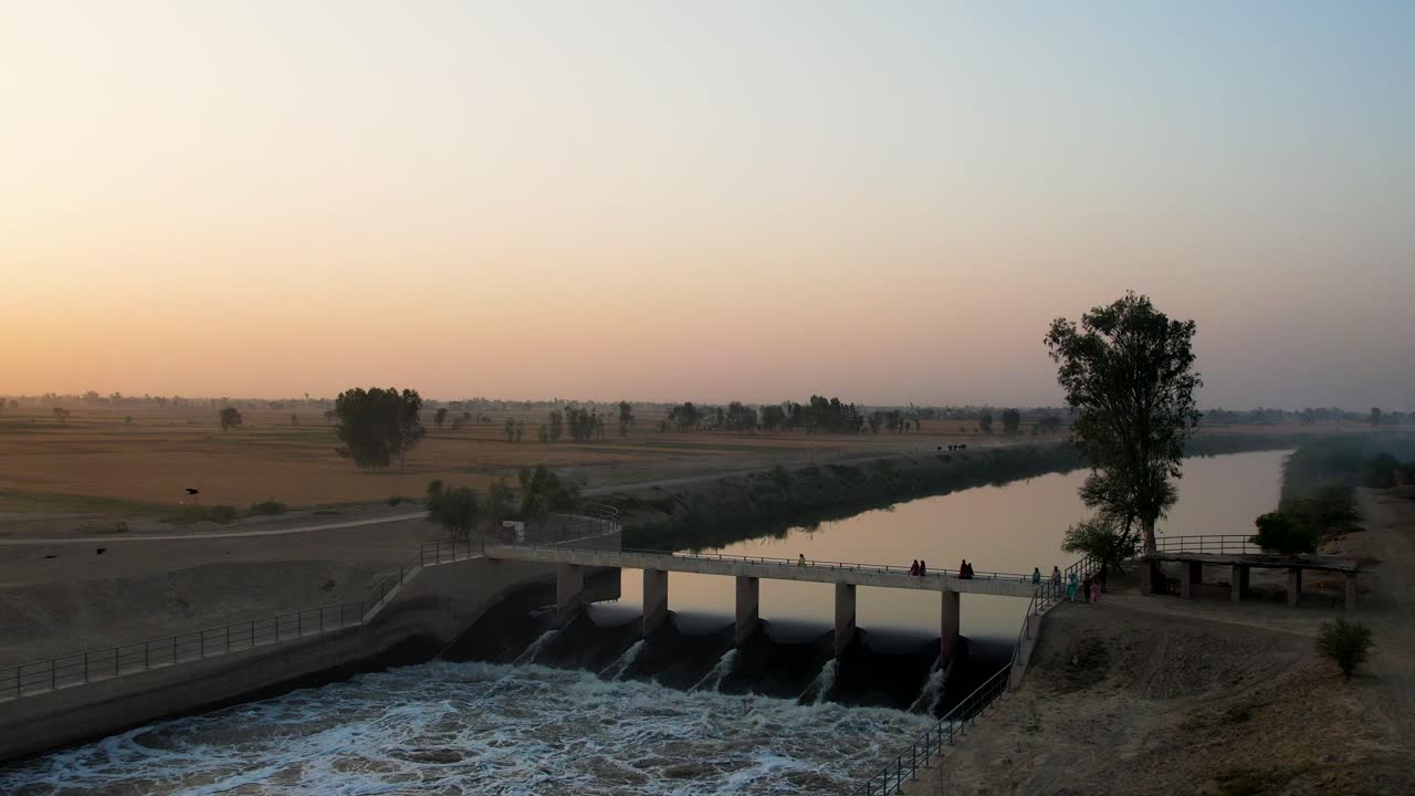 Golden hour at a canal bridge with flowing Sutlej waters and vast wheat fields. Punjab, Pakistan