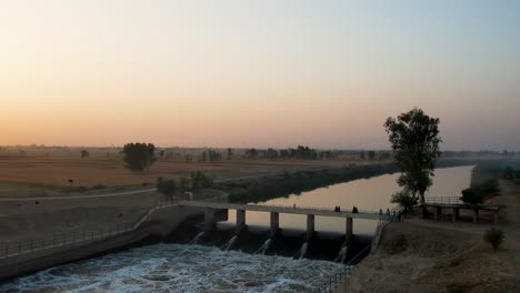 golden hour at a canal bridge with flowing sutlej waters and vast wheat fields. punjab, pakistan