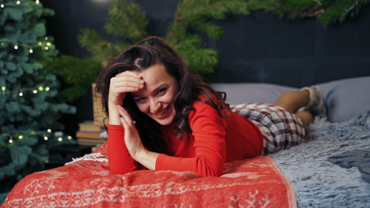 Pretty woman closes eyes with hands and making cuckoo jesture. Red sweater ona nice girl. New year decorations.