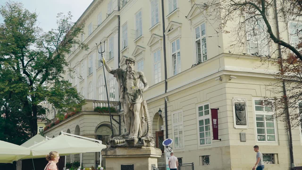 Architectural monument in the city center and tourists walking around and taking photos. Ancient memorial in the central street of a town.