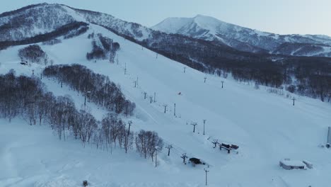 stationary shot of a snow groomer grooming the open runs of a back country ski slope before opening hours in hokkaido, japan.