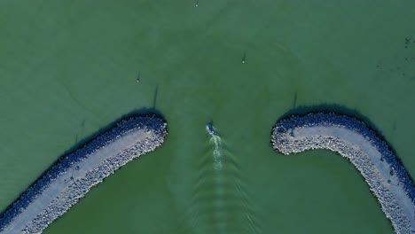 Tracking-shot-of-a-jetski-exiting-the-Saratoga-Marina-on-Utah-Lake-between-the-channel-markers-creating-white-spray-and-leaving-a-trail-of-wash-amongst-emerald-green-water