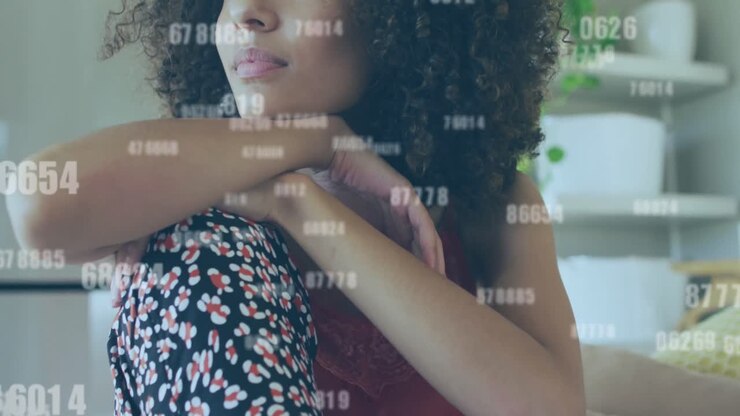Animation of multiple changing numbers against thoughtul african american woman sitting at home