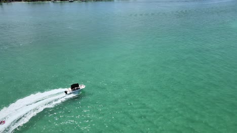 Die-Kamera-Fliegt-über-Den-Ozean-Und-Sinkt-In-Die-Höhe,-Während-Ein-Boot,-Das-Ein-Schleppbares-Schlauchboot-Zieht,-Den-Weg-Der-Kamera-Kreuzt