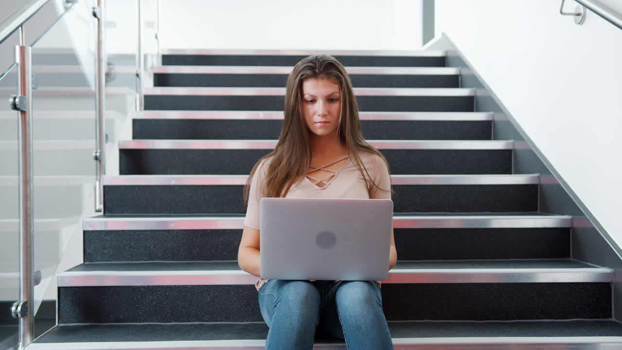Female High School Student Sitting On Staircase And Using Laptop