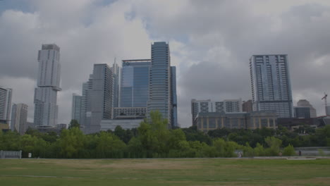 Pan-left-to-right-on-Austin,-Texas-skyline-with-people-running-and-walking-in-distance