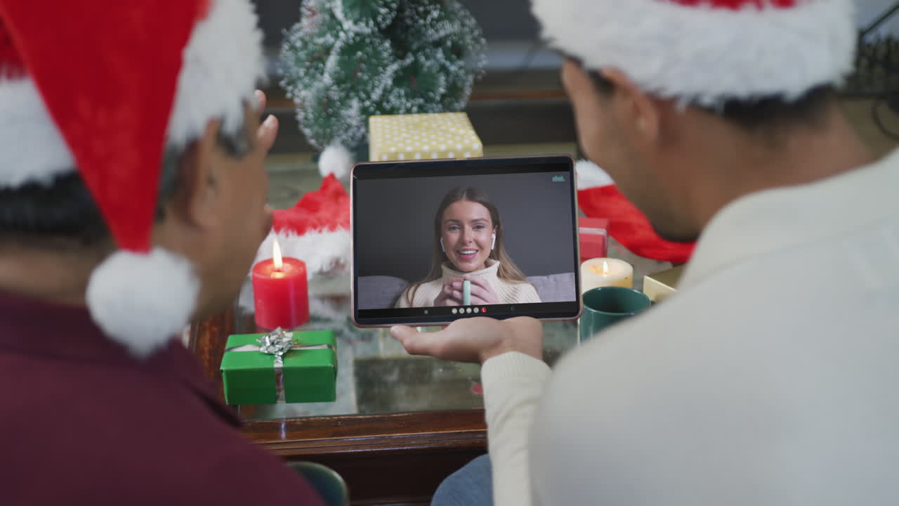 padre biracial con hijo agitando y usando la tableta para la videollamada de navidad con la mujer en la pantalla