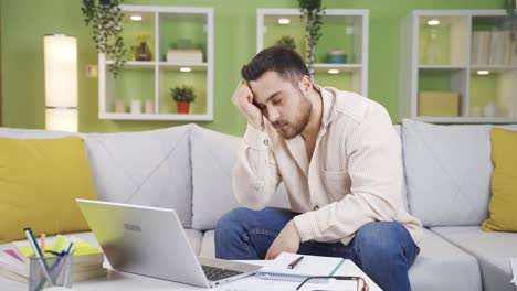 joven trabajando en la computadora portátil en casa soñoliento y cansado.