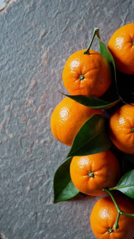 fresh oranges and green leaves on a textured surface