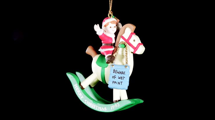 single wooden Christmas ornament of a boy on a rocking horse with black background, close up