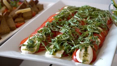 platter with tomatoes, mozzarella, arugula, and pesto