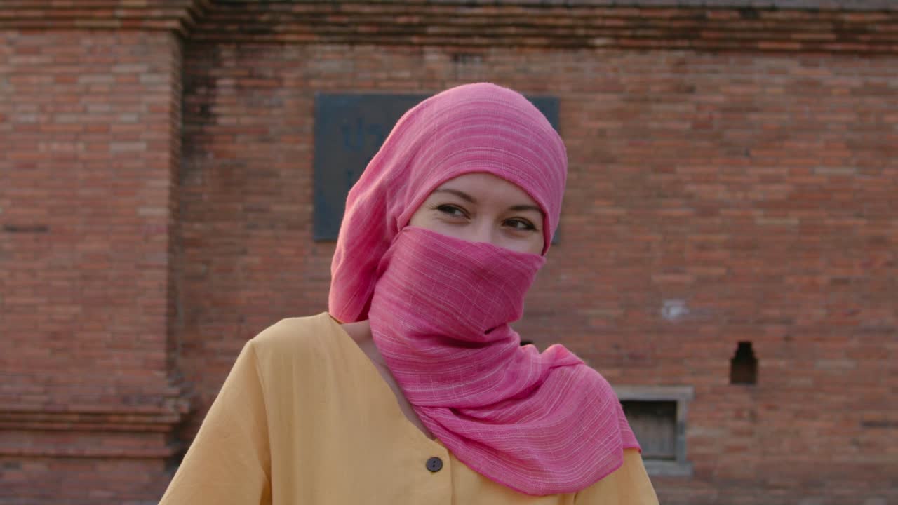 Woman in Pink Hijab in Front of Brick Wall
