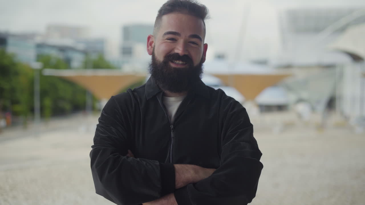 un joven sonriente y confiado posando al aire libre.