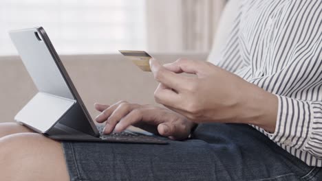 mano de mujeres jóvenes están comprando en línea con tarjeta de crédito mientras están sentadas en el sofá. la mujer está usando tableta y haciendo transacciones en línea.