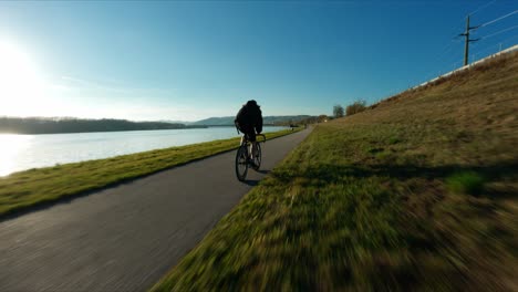 tiro rápido fpv del ciclista de carreras jake el ciclista de equipo fijo junto al río danubio en el colorido día de otoño