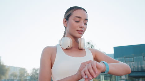 young female runner looks at smartwatch device fitness bracelet heart rate pulse spo2 in city park