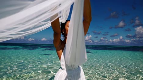 woman on a beach in a white dress with a veil in the wind