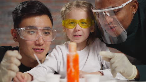 amazed girl with chemistry teachers looks at active reaction