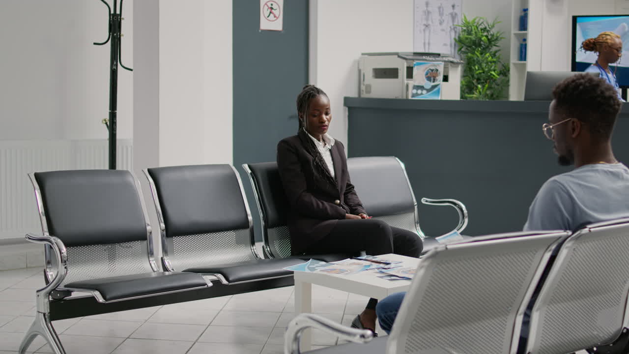 Female nurse consulting young woman in hospital waiting area