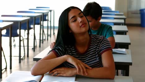 Chica-Somnolienta-Relajándose-En-El-Escritorio-Mientras-Estudia-En-El-Aula