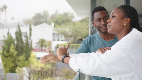 standing on balcony, young african american couple discussing view outside home, copy space