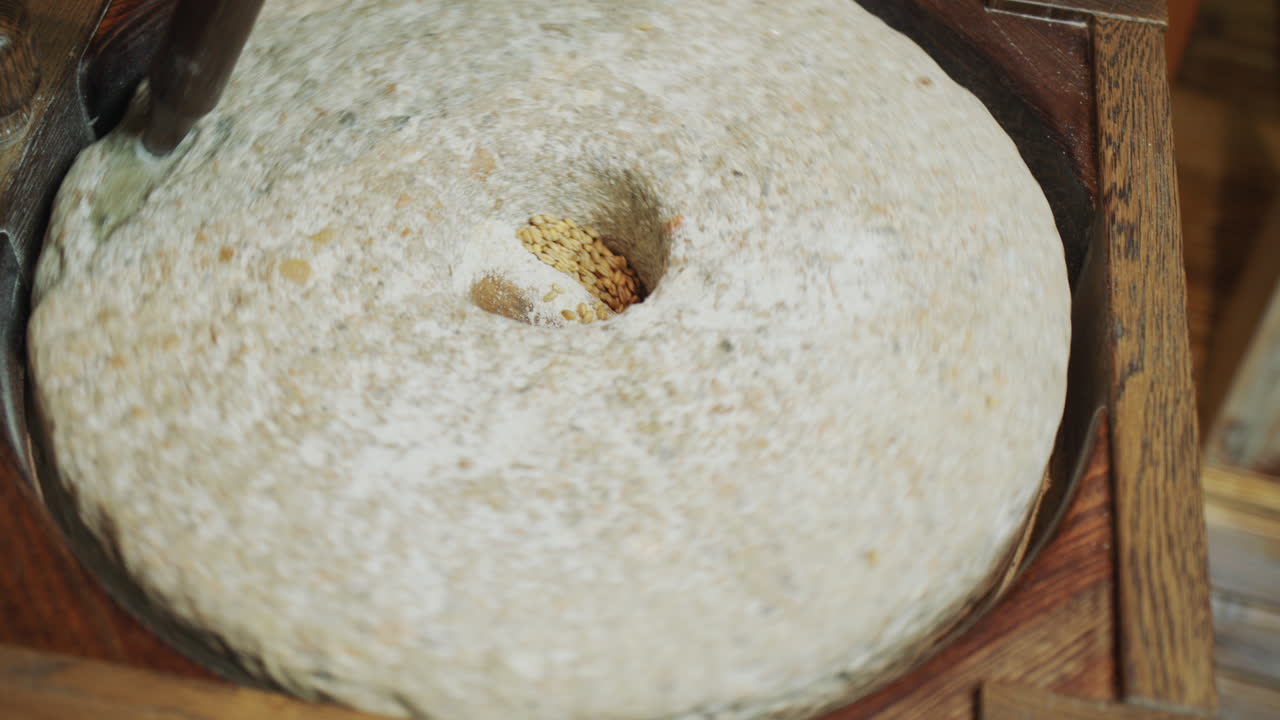 The baker grinds grain into flour. Antique hand mill in operation with an authentic 200 year old millstone