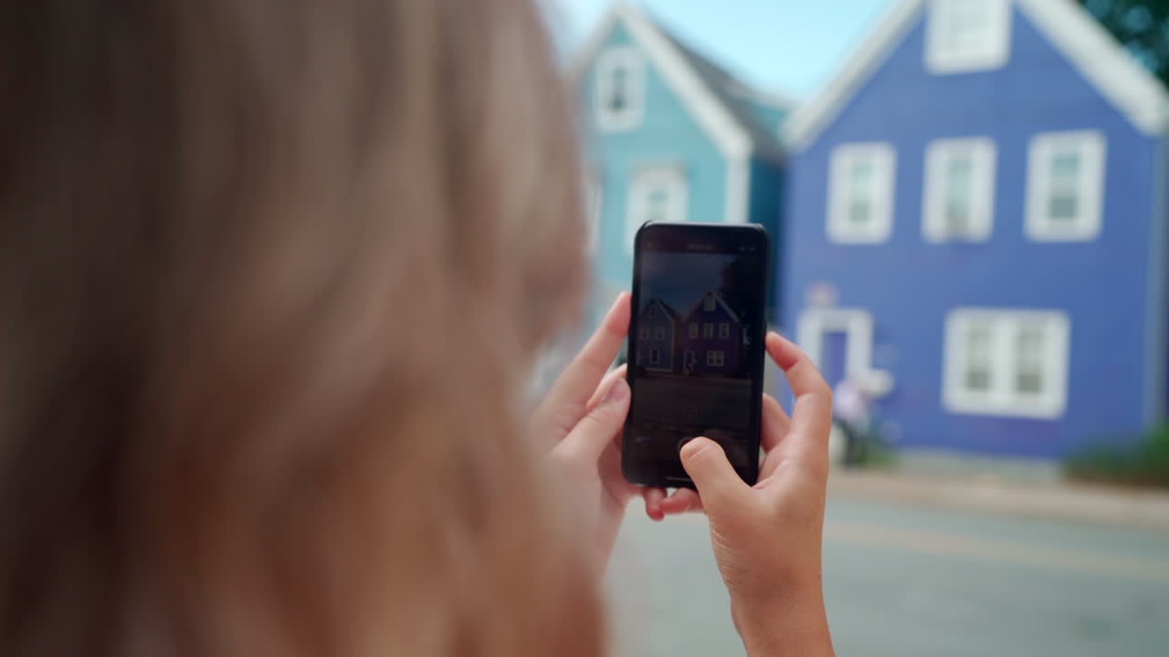 mujer tomando fotos de edificios coloridos en su teléfono celular en halifax, nueva escocia, canadá