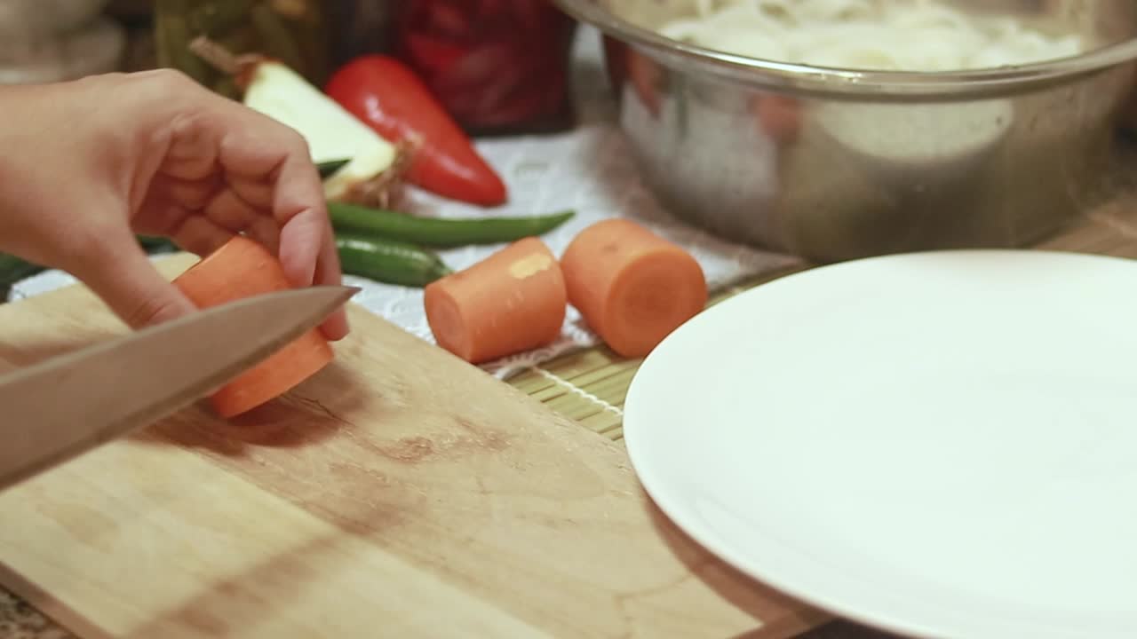 Slicing raw carrots on a wooden cutting board, cozy kitchen scene showing the candid moments of daily life at home