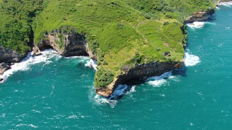 cliff shoreline of gesing beach, turquoise ocean waves hitting rocks, indonesia