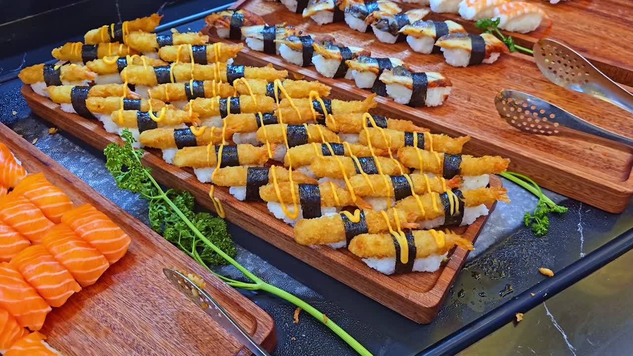 Camera moves closer to trays filled with sushi and tempura rolls neatly arranged in a restaurant display