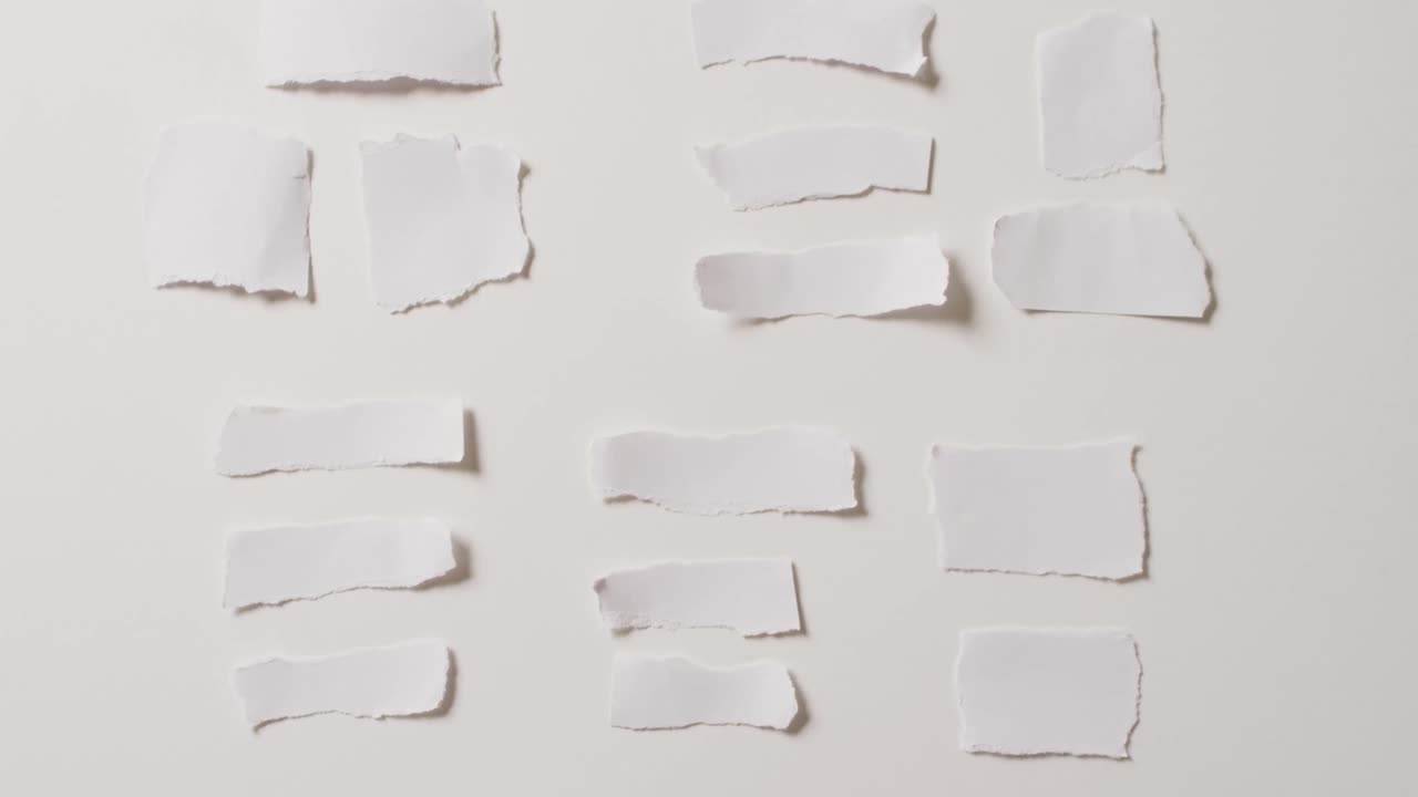 video de un primer plano de varias piezas de papel rasgadas sobre un fondo blanco