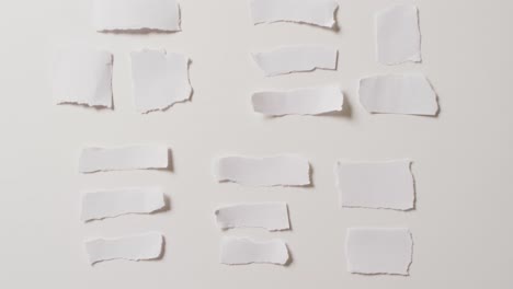 video of close up of multiple torn pieces of paper on white background