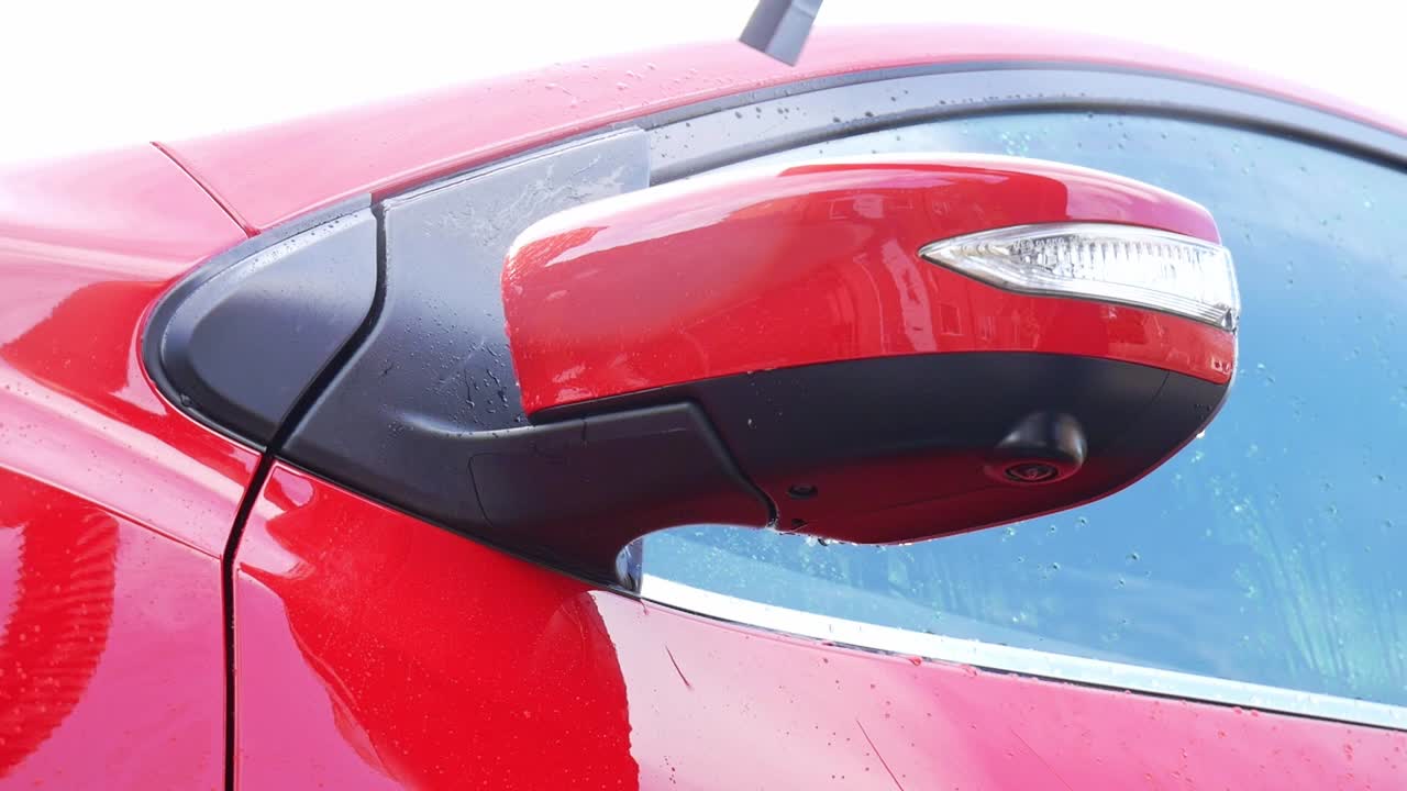 Drying a red car wing mirror with an electic blow dryer