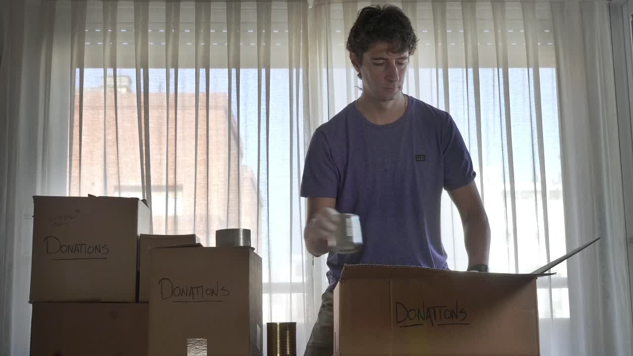 Joven empaquetando donaciones de alimentos en cajas de cartón.