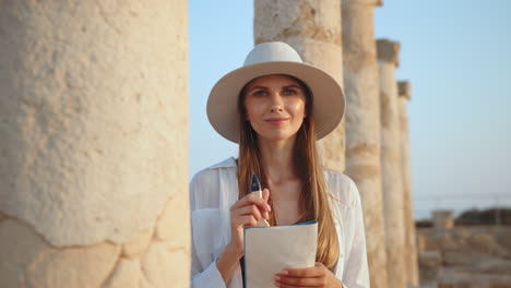 mujer escribiendo en un cuaderno cerca de antiguas ruinas