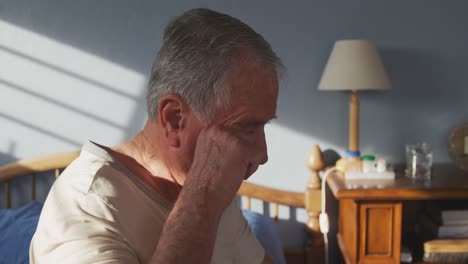 senior man sitting on bed at home