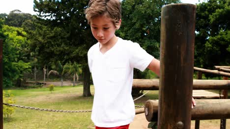 boy walking on a playground ride in park