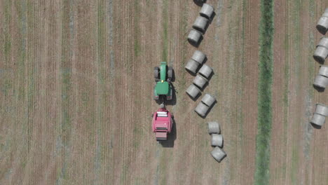 Toma-Aérea-De-Arriba-Hacia-Abajo-Del-Tractor-Pasando-Por-Pacas-Redondas-De-Heno