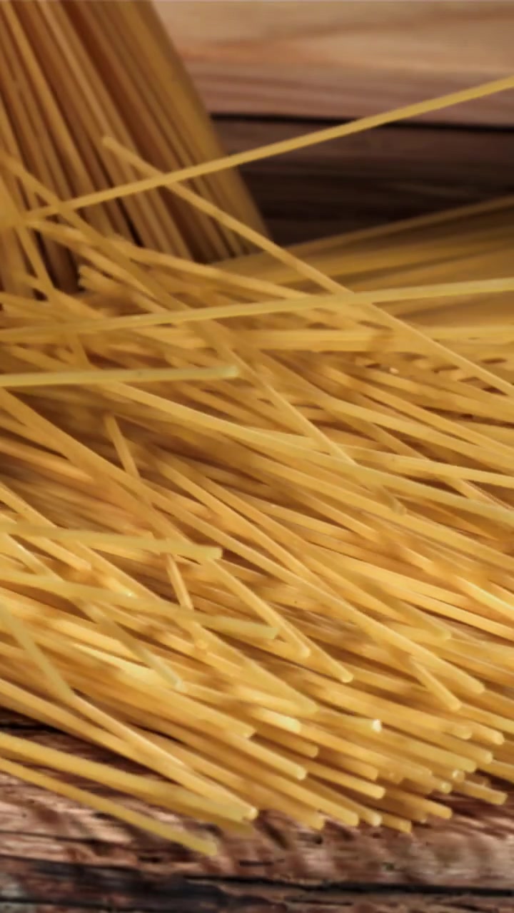 Spaghetti secchi che cadono su una superficie di legno rustico