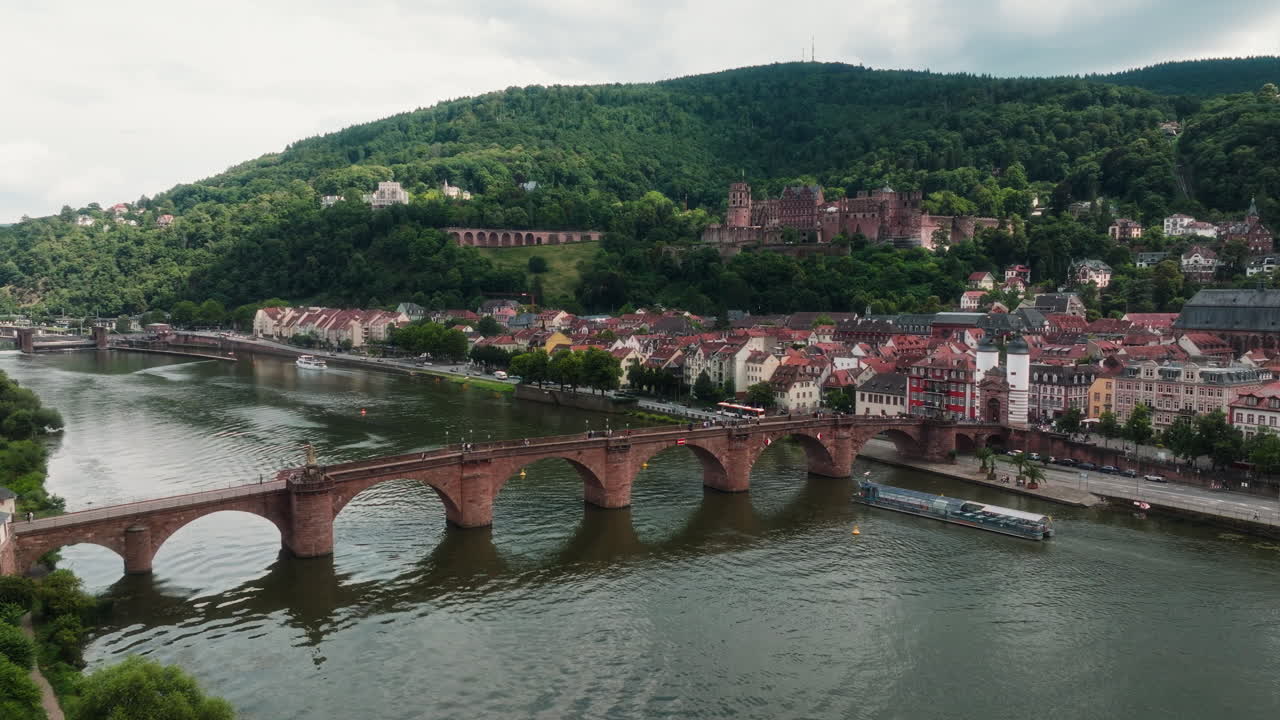Ripresa laterale con drone che segue il Ponte Vecchio sul fiume Neckar verso la collina del Castello di Heidelberg