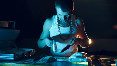 drug dealer takes a package with a drug and cuts it with a knife to sample it. abuse of drugs. criminal business